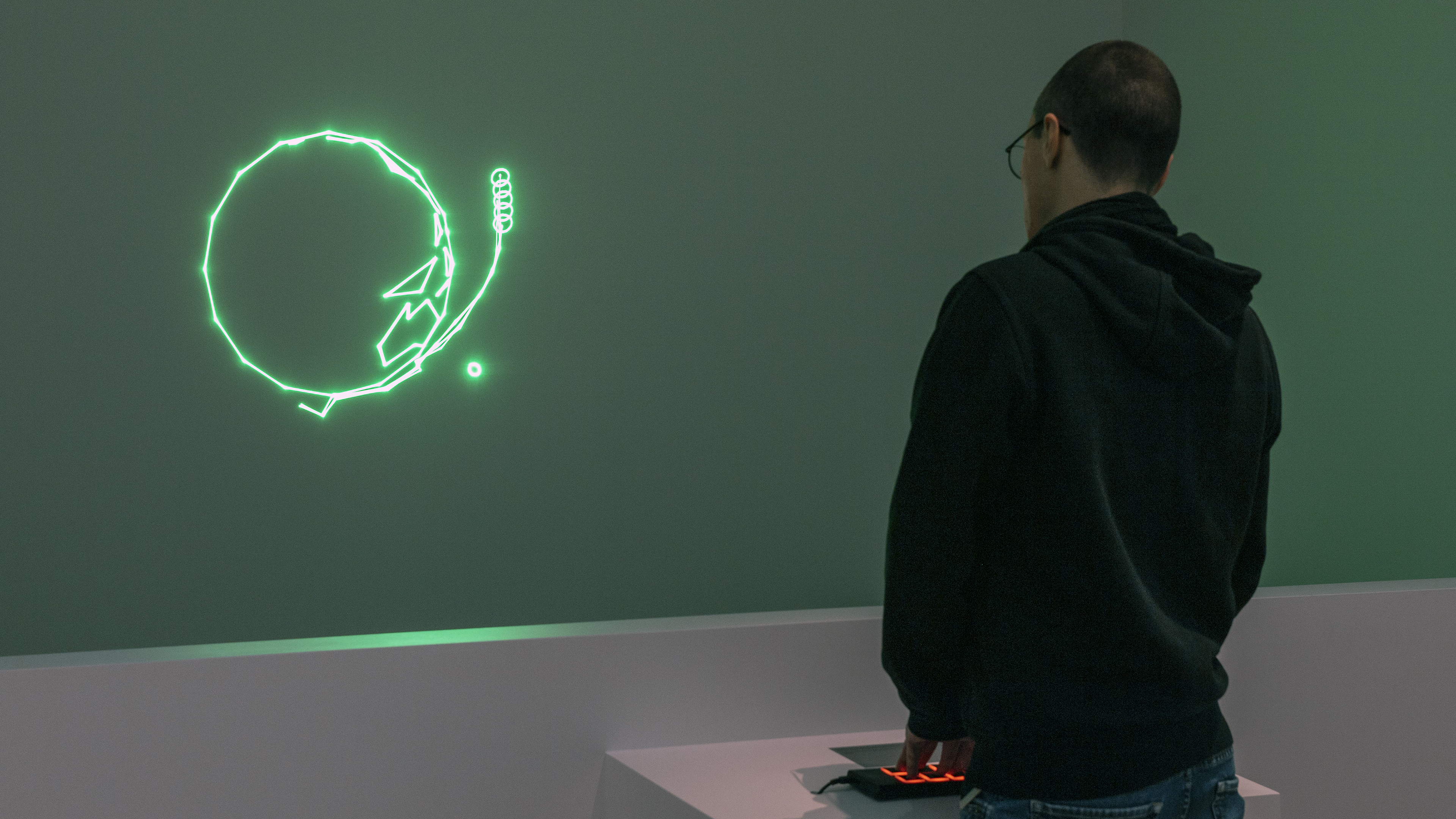 A person pressing buttons in front of a jittery green laser image of earth with a circle in its orbit.